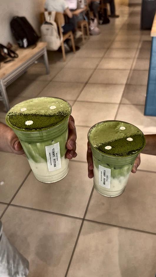 Two Matcha House drinks held up, dusted matcha with a flower on top